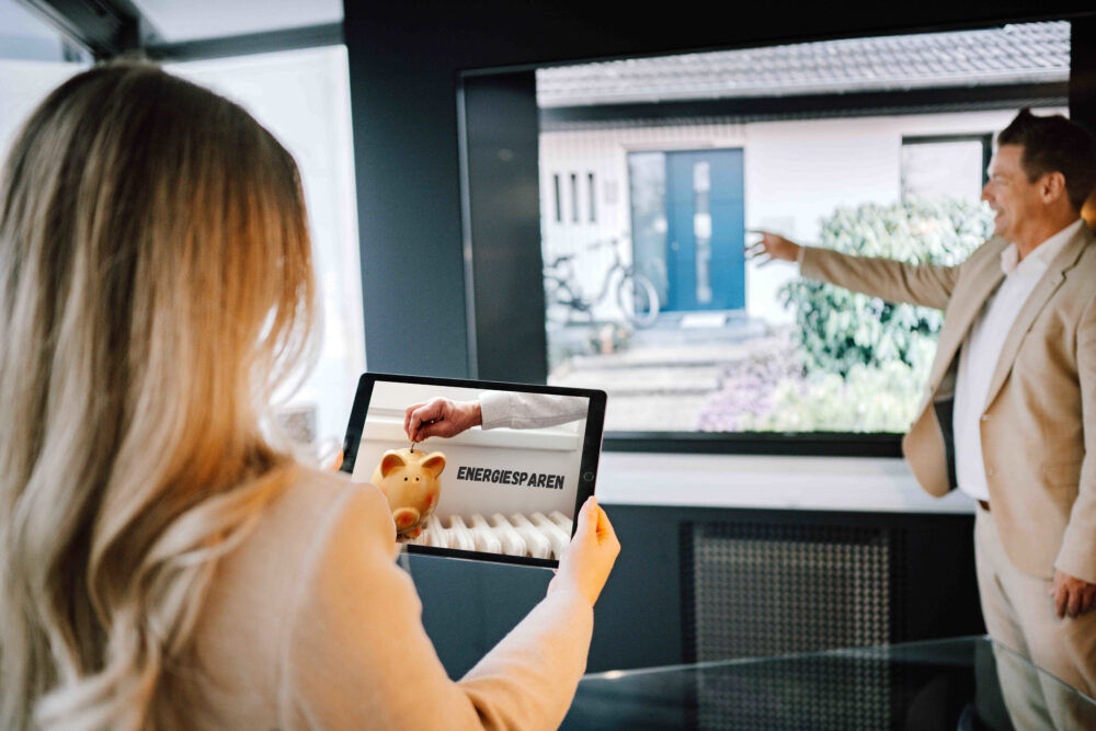 Eine Frau sieht auf einem Tablet ein Bild von einer Spardose mit der Aufschrift "Energiesparen".