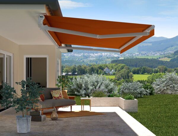Eine orangefarbene Markise über einer Terrasse mit Blick auf eine hügelige Landschaft.